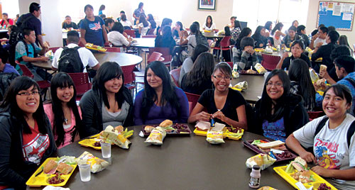 Young Native American Girls sitting down having lunch at a round table in the schools cafeteria.
